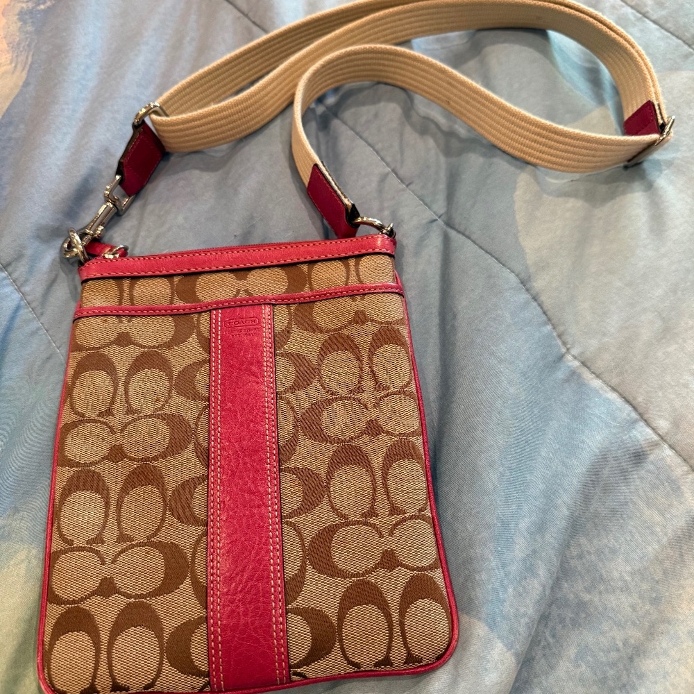 Coach signature canvas crossbody bag with a pink leather trim and strap accents.